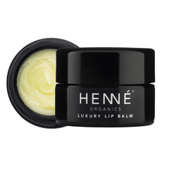 Henné Organics Luxury Lip Balm black glass jar beside its open lid showing creamy pale yellow balm