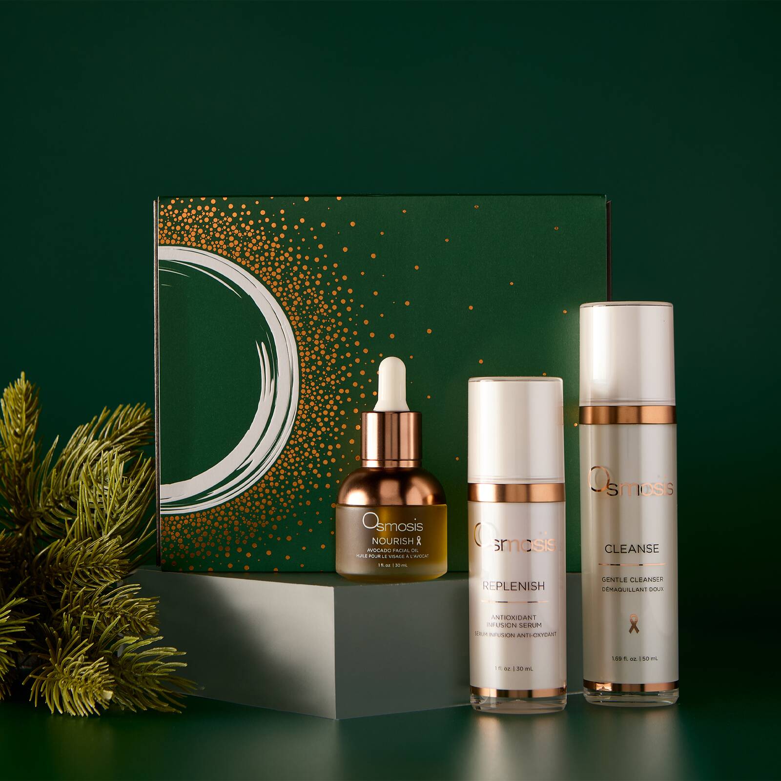 Osmosis Let It Glow Kit gift box with Nourish Replenish and Cleanse displayed on pedestals with pine branches