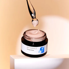 Rationale The Eye Crème open jar with dropper applicator showing pink cream texture on warm beige background
