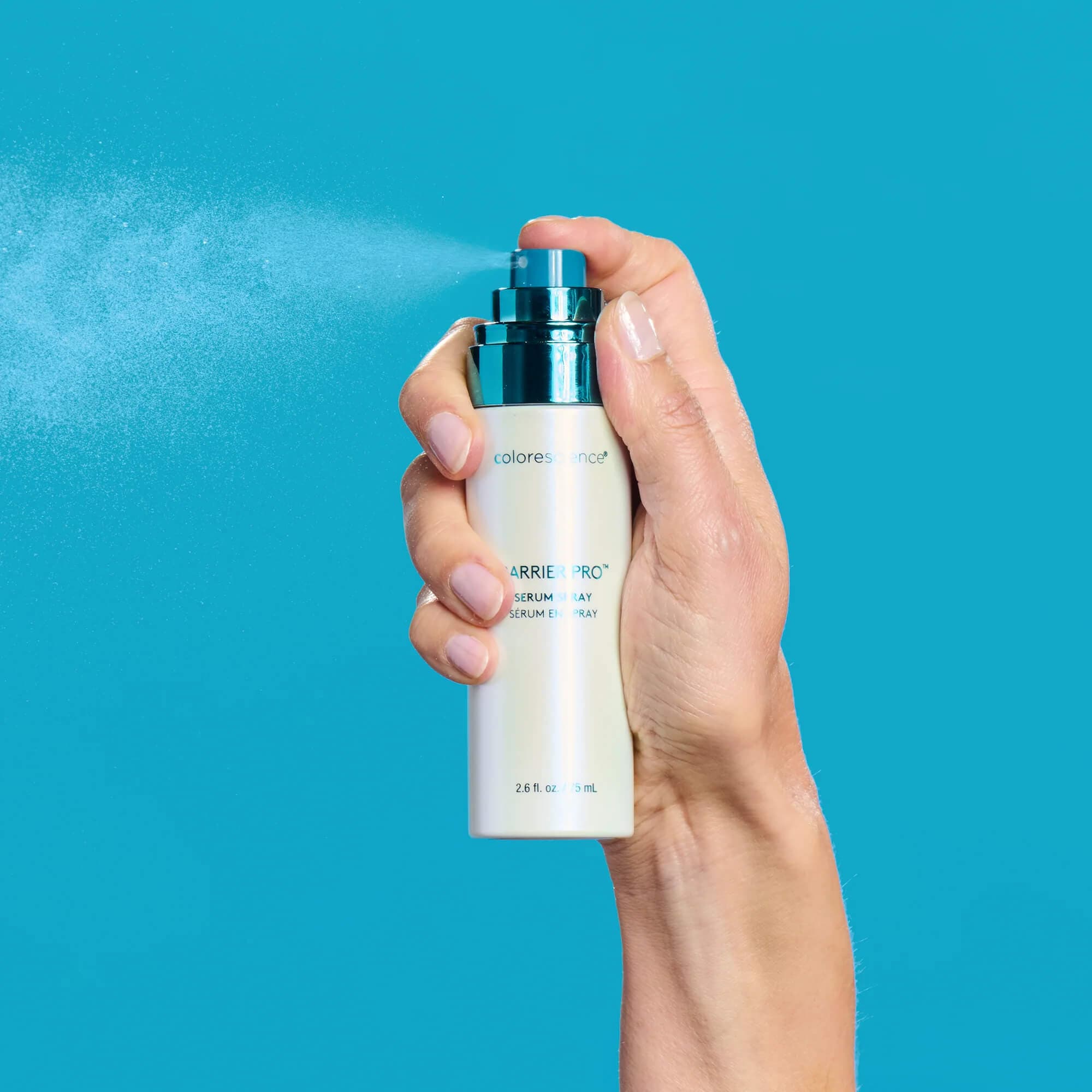 Hand holding a bottle of Colorescense Barrier Pro Serum against a blue background