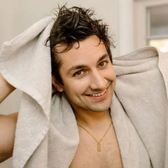 Man wrapped in a towel, smiling indoors