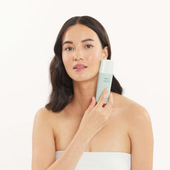 Woman holding a skincare product against a white background