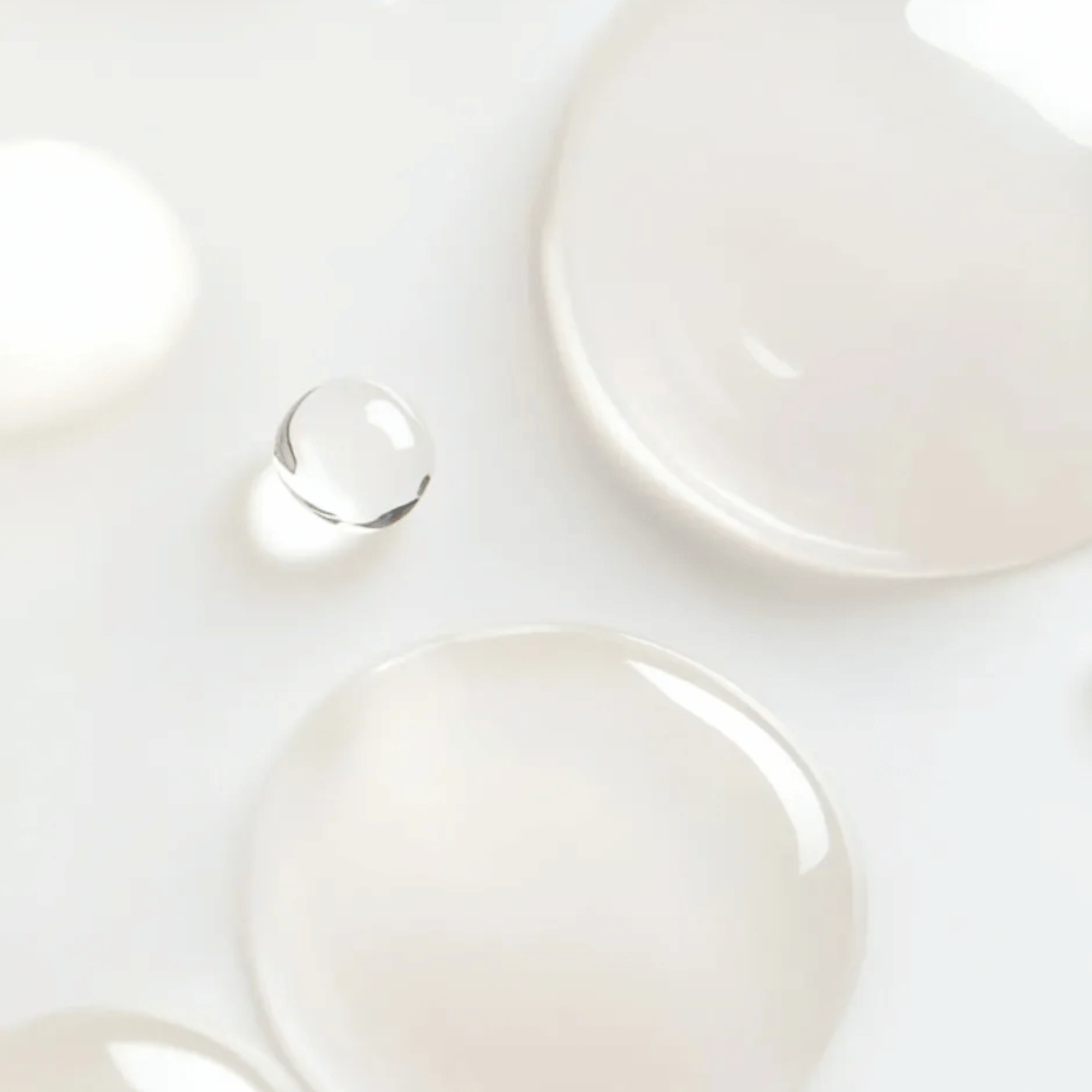 Close-up of lightweight reparative serum droplets on white surface showing silky texture