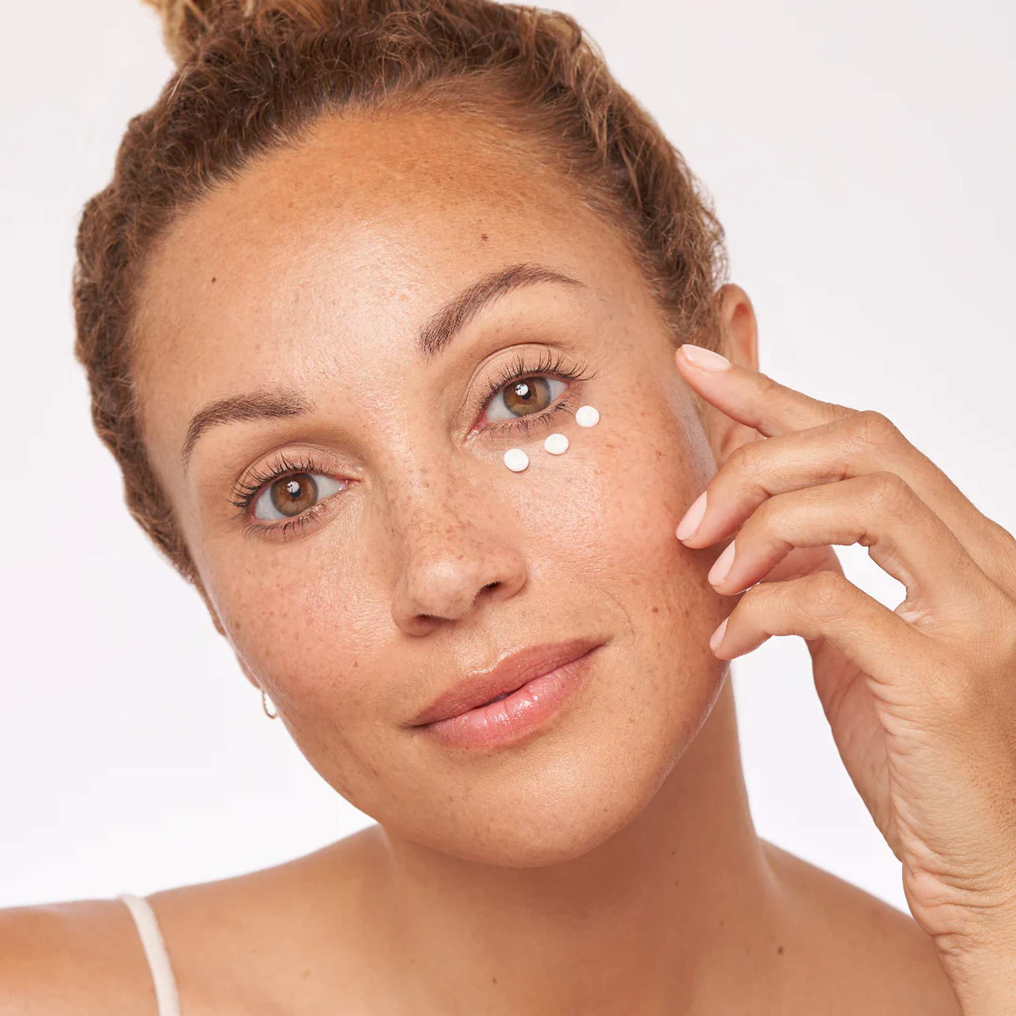 Woman applying ALASTIN Restorative Eye Complex under the eye to help reduce puffiness and dark circles