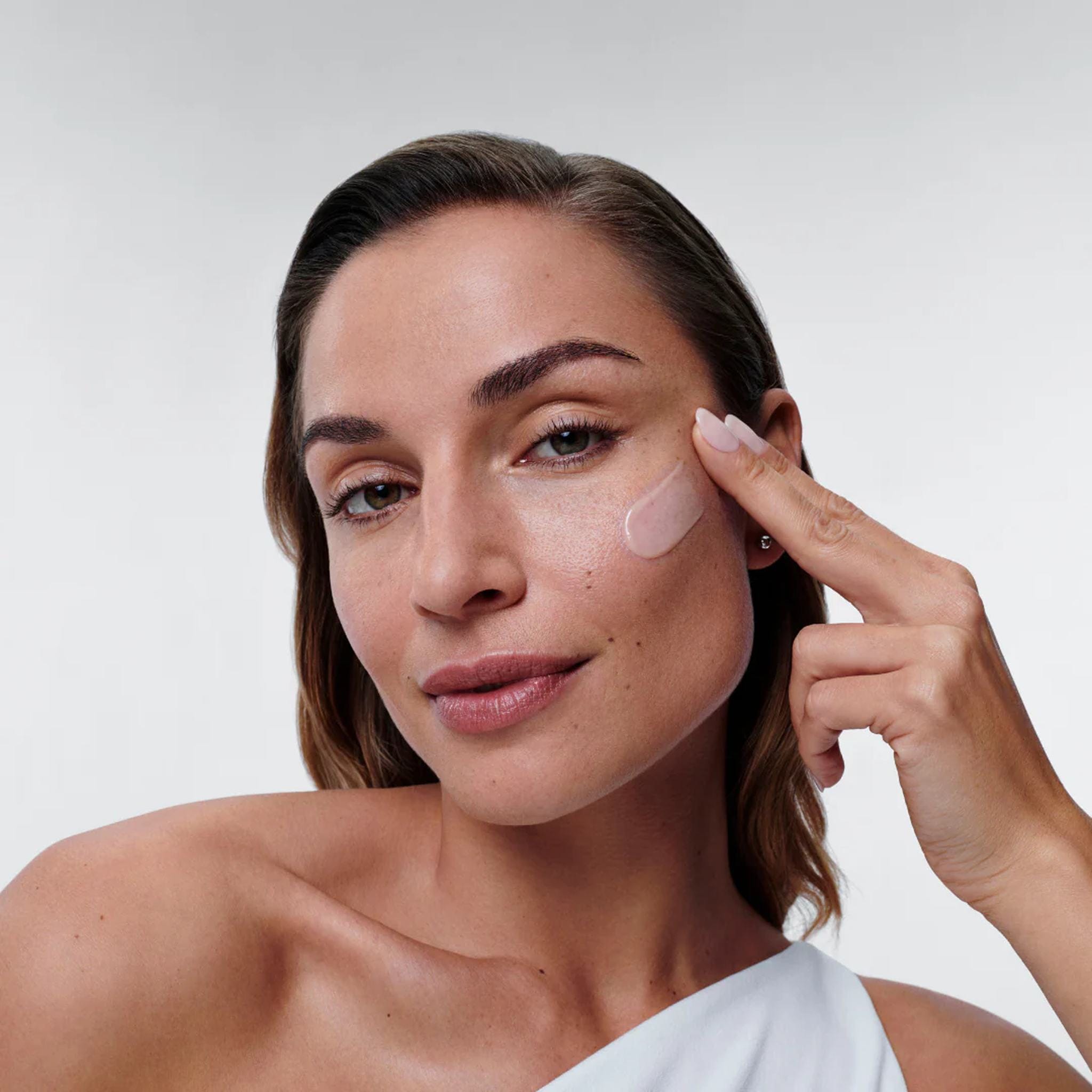 Woman applying ALASTIN Restorative Skin Complex anti-aging cream to her cheek