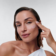 Woman applying ALASTIN Restorative Skin Complex anti-aging cream to her cheek