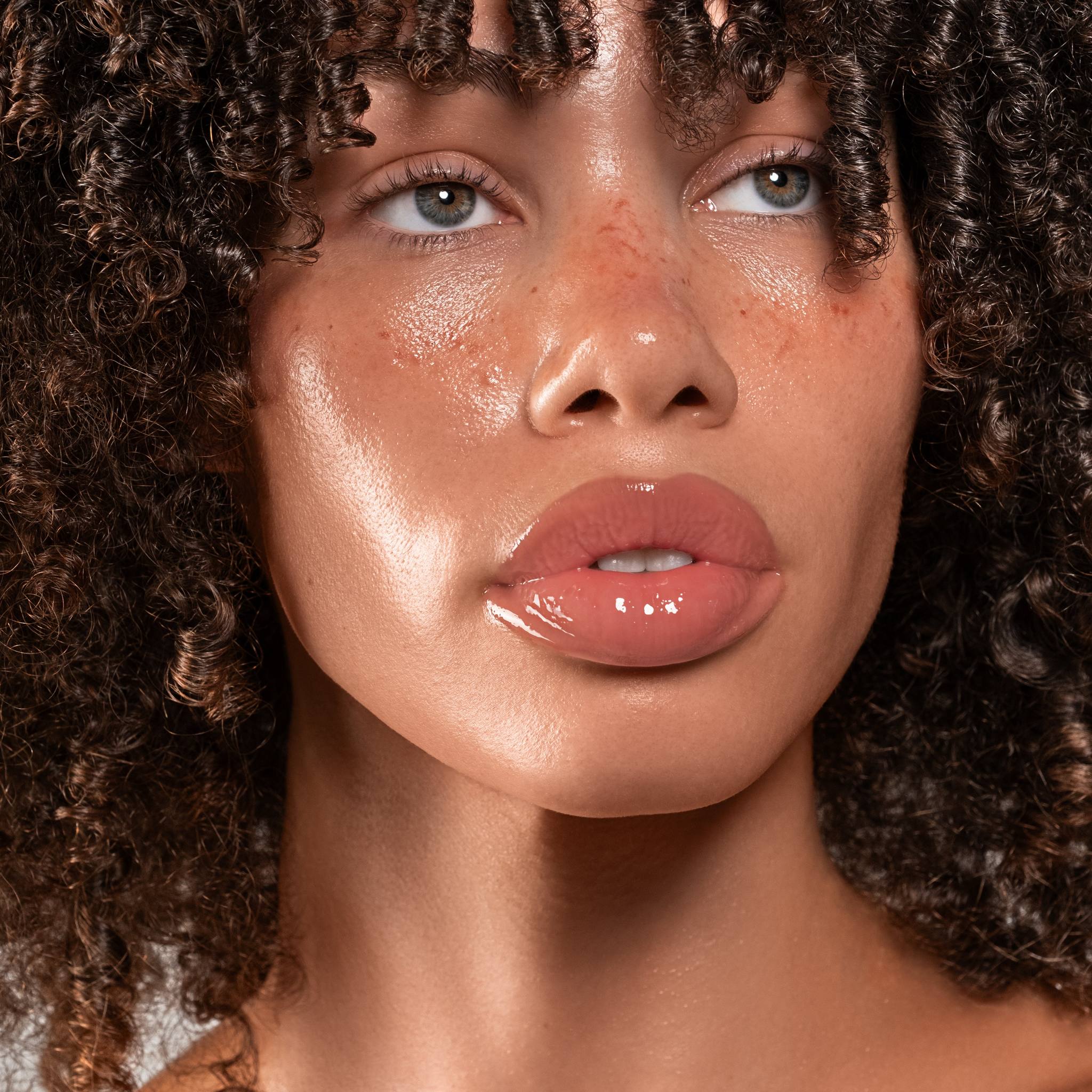Model with curly hair wearing Anfisa Skin AN-Gloss Ceramide Lip Tint Berry Crumble for glossy plump lips 7