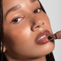 Model with braids applying Anfisa Skin AN-Gloss Ceramide Lip Tint in Spice Cake with roller applicator 3