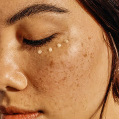 Close-up of a person's face with freckles and a small droplet on their cheek.