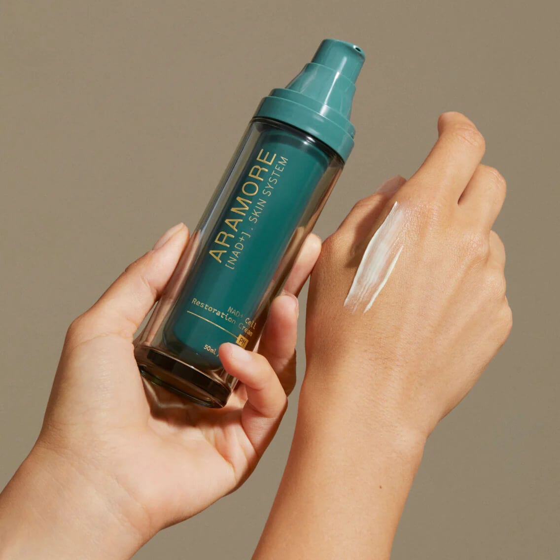 Hand holding a bottle labeled 'Aramore' with another hand applying a product to the skin.