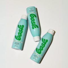Three Bask SPF 30 mineral sunscreen spray bottles arranged in flatlay showing teal and green packaging