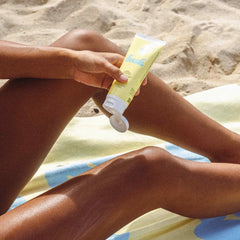 Bask SPF 30 moisturizing sunscreen lotion being applied to legs on beach towel with sandy beach background