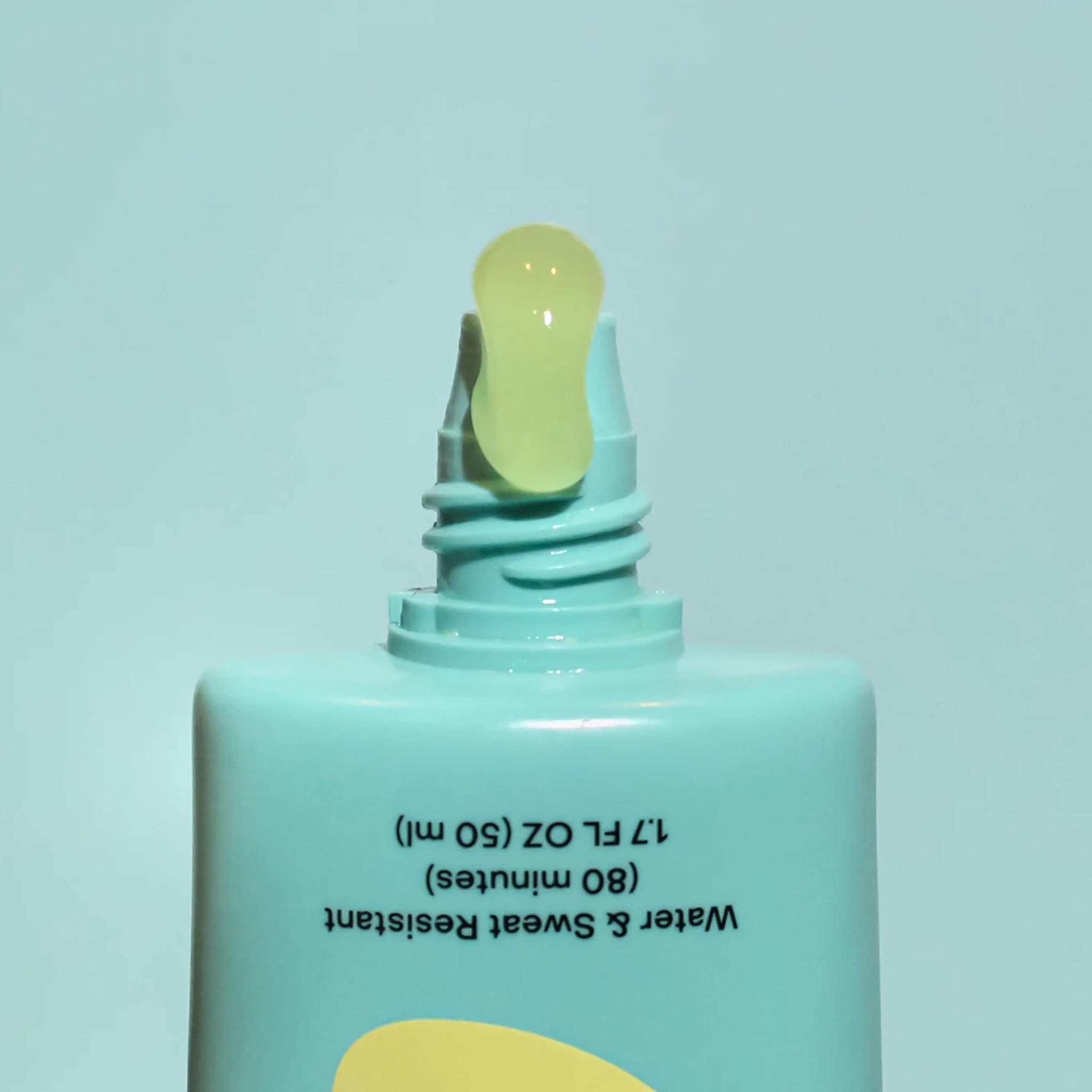 Closeup of Bask SPF 40 daily invisible gel sunscreen tube open nozzle dispensing clear gel on teal background