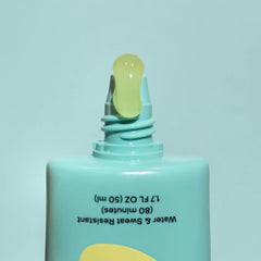 Closeup of Bask SPF 40 daily invisible gel sunscreen tube open nozzle dispensing clear gel on teal background