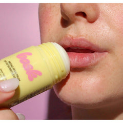 Closeup of Bask SPF 50 sunscreen stick being applied to lips showing delicate face use on pink background