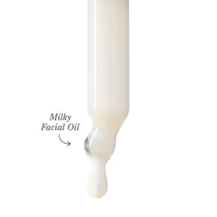 Milky facial oil dripping from a dropper showing its lightweight texture