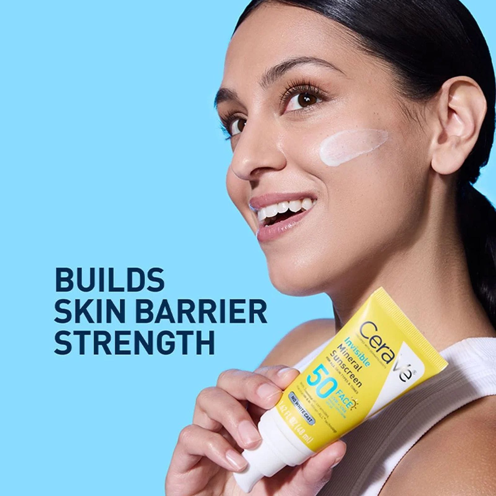 Woman with sunscreen swatch on cheek holding CeraVe Invisible Mineral Sunscreen that builds skin barrier strength