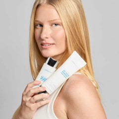 Model holding two Colorescience No-Show Mineral Body Shield SPF 50 sunscreen tubes against shoulder