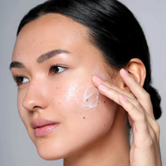 Woman applying Cosmedix Harmonize microbiome boosting moisturizer to her cheek