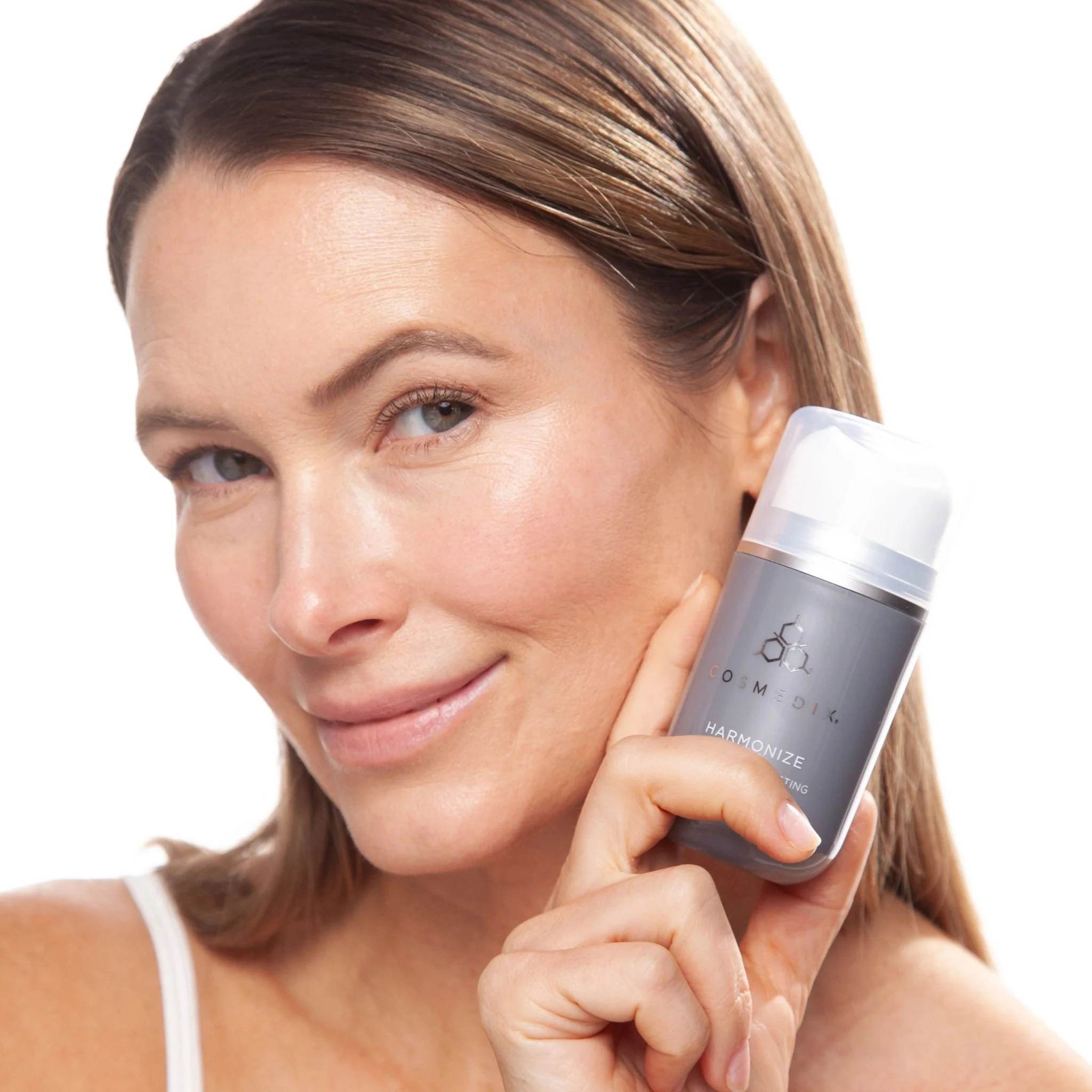 Woman holding Cosmedix Harmonize microbiome boosting moisturizer near her face