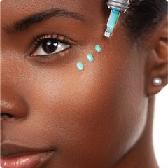 Woman applying Cosmedix Opti Crystal eye serum droplets under her eye