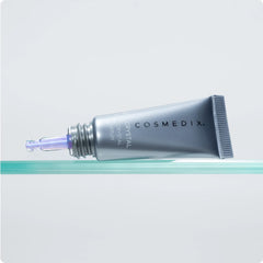 Cosmedix Opti Crystal eye serum tube resting on glass surface