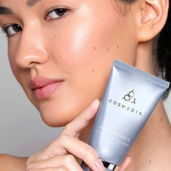 Woman holding Cosmedix Pure Enzymes cranberry exfoliating mask near her face