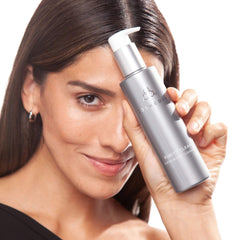 Woman holding Cosmedix Purity Clean exfoliating cleanser near her face