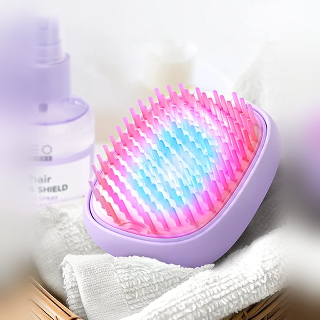 FOREO FLIP plus lavender hair brush glowing with pink and blue LED light on a towel beside hair spray