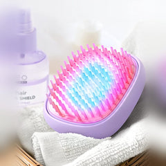 FOREO FLIP plus lavender hair brush glowing with pink and blue LED light on a towel beside hair spray