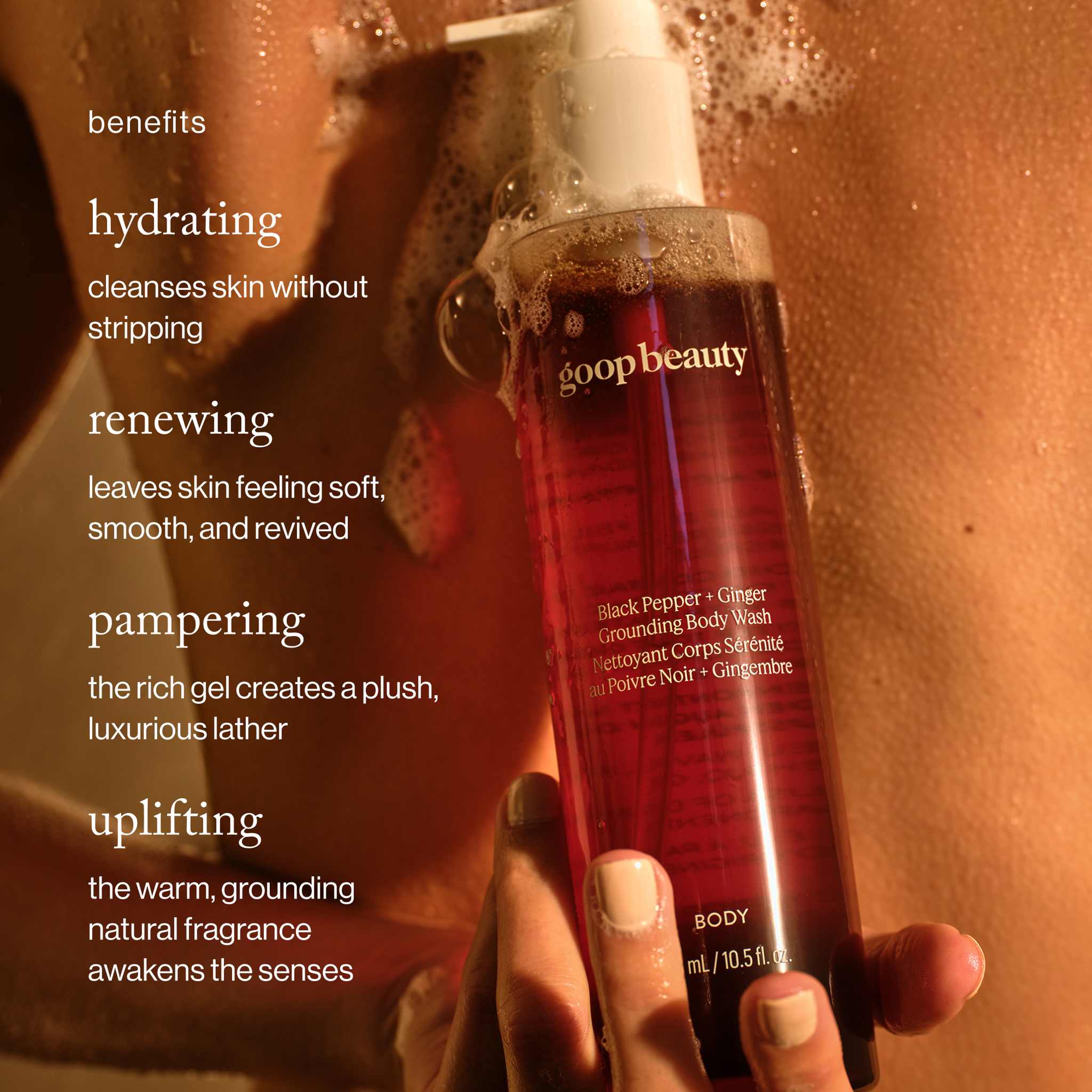 benefits: Hand holding goop beauty Black Pepper Ginger body wash bottle with rich lather during a shower