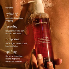 benefits: Hand holding goop beauty Black Pepper Ginger body wash bottle with rich lather during a shower