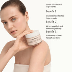 goop beauty Himalayan Salt Scalp Scrub Shampoo held by model highlighting 3 key benefits: cleanses detoxifies and leaves hair soft
