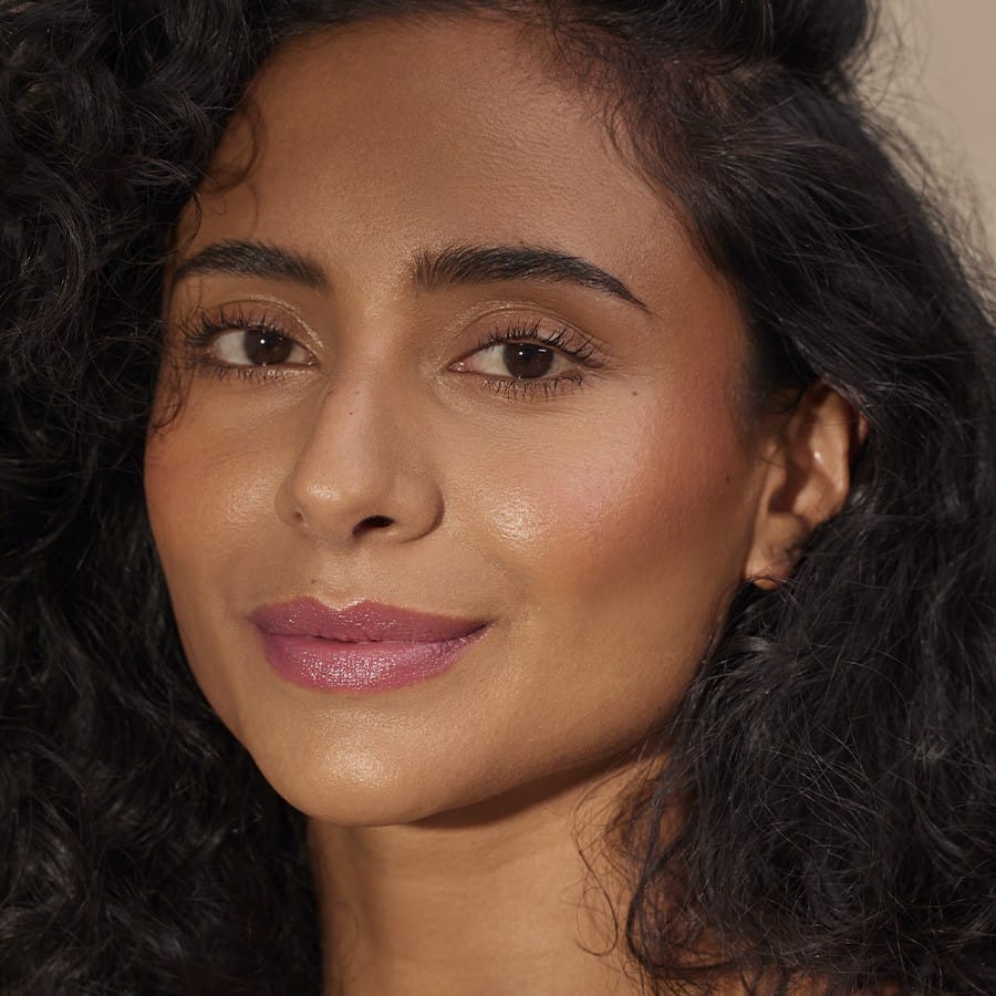 Woman with curly hair wearing Henné Organics Luxury Lip Tint in Azalea for a sheer orchid pink lip 4