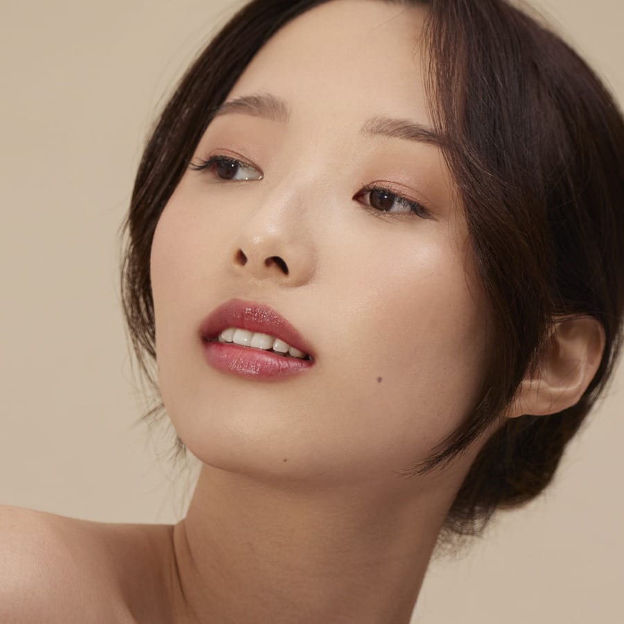 Model wearing Henné Organics Luxury Lip Tint in Blissful for glossy hydrated lips with sheer berry color 3