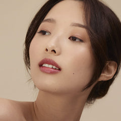 Model wearing Henné Organics Luxury Lip Tint in Blissful for glossy hydrated lips with sheer berry color 3