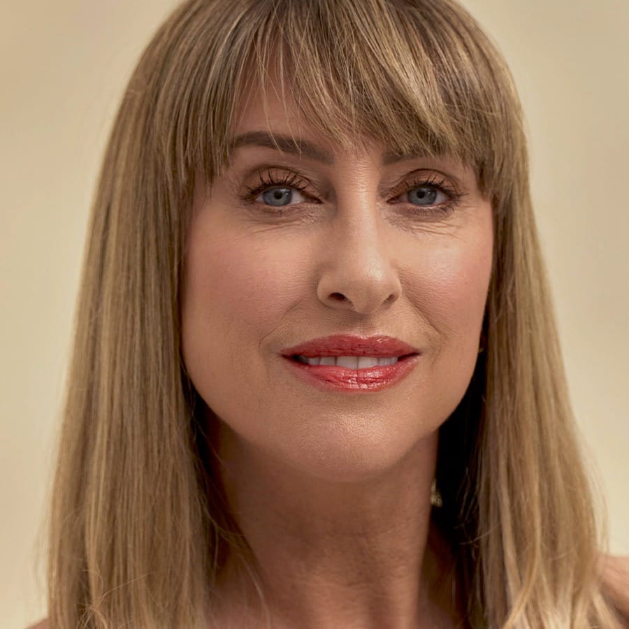 Smiling woman with blonde bangs wearing Henné Organics Luxury Lip Tint in Desire for a warm red lip 5