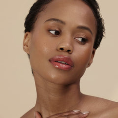 Woman with short curls and deep skin tone wearing Henné Organics Luxury Lip Tint in Desire 4