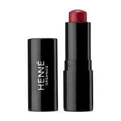 Henné Organics Luxury Lip Tint in Desire uncapped beside its black cap showing the sheer cherry red balm 1