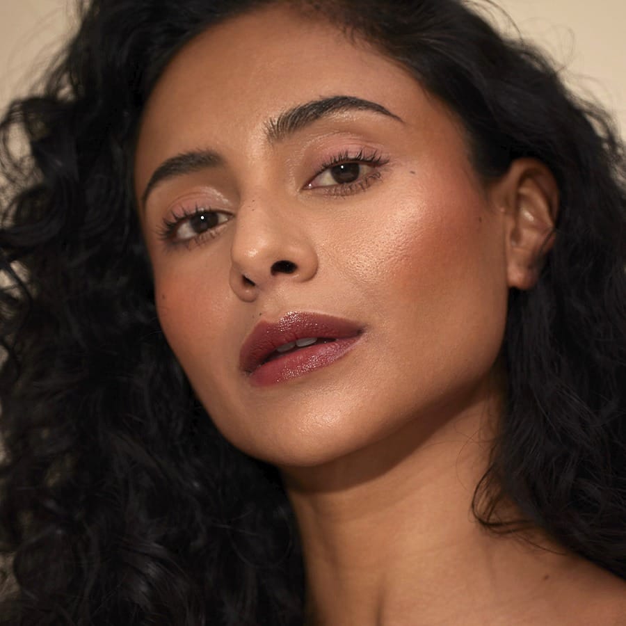 Woman with curly hair wearing Henné Organics Luxury Lip Tint in Intrigue for a rich berry brown lip 3