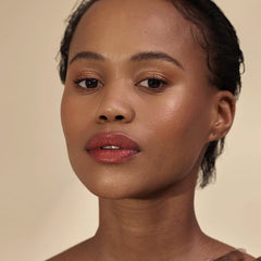 Woman with short curls and deep skin tone wearing Henné Organics Luxury Lip Tint in Intrigue 5