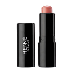 Henné Organics Luxury Lip Tint in Sunlit uncapped beside its black cap showing the sheer peachy pink balm 1