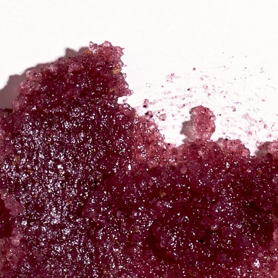 Swatch of Nordic Berries lip exfoliator showing fine sparkling sugar crystals in a deep berry tone