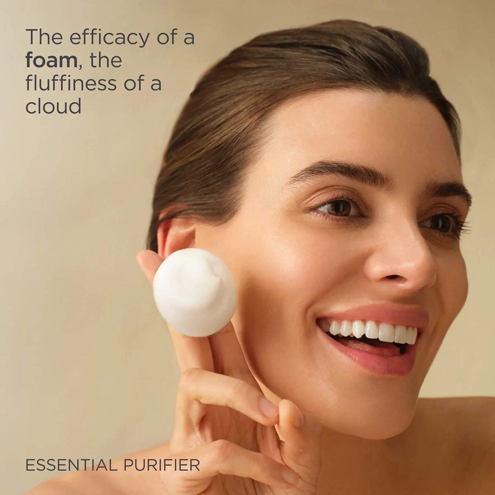 Woman holding a cloud of ISDIN Essential Purifier foam cleanser beside her face