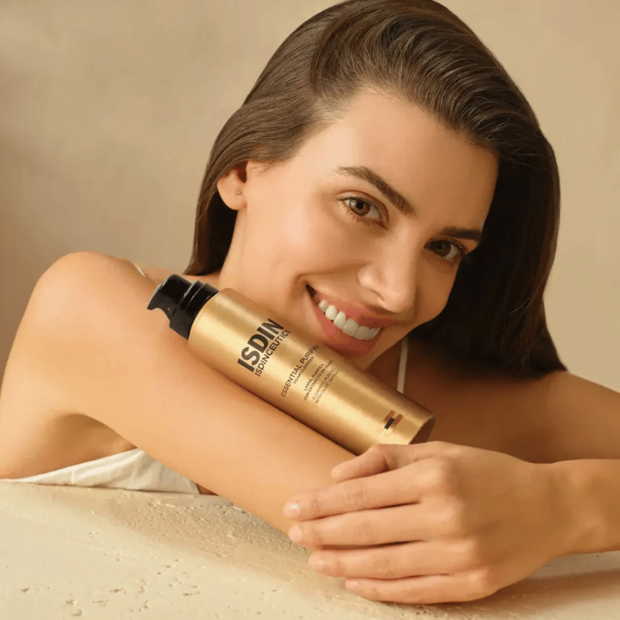 Woman holding a gold and black bottle against a beige background