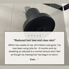 Black shower head on a tiled wall with a customer review overlay.