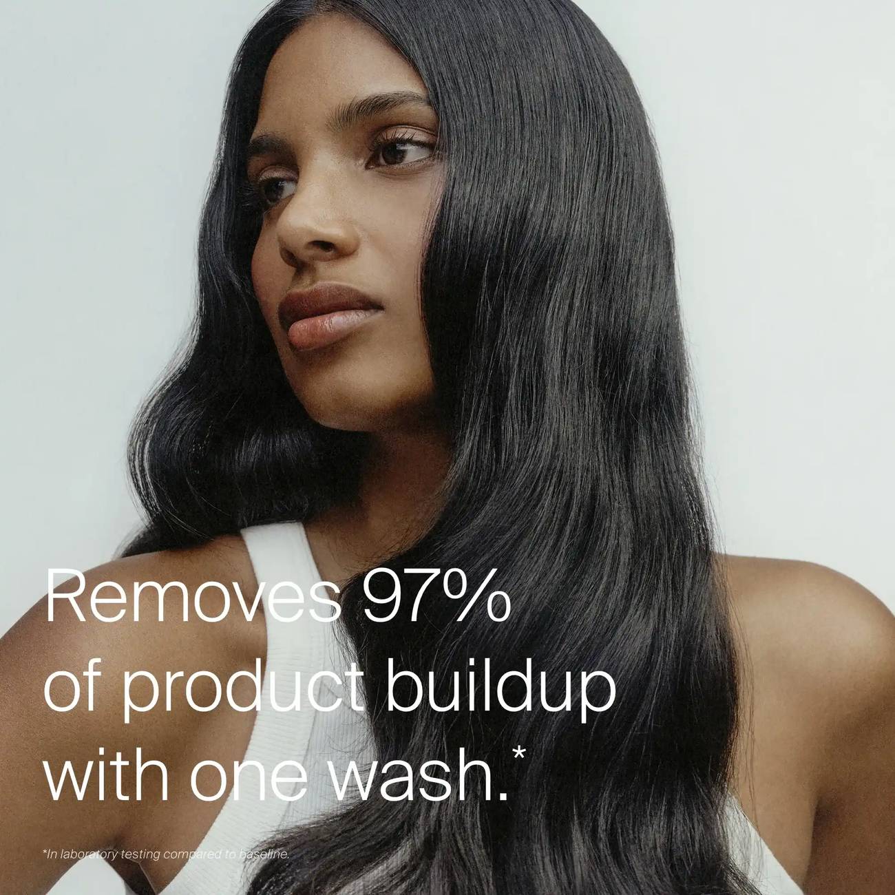 Woman with long glossy dark hair showing Living Proof Clarifying Detox Shampoo removing 97 percent of product buildup