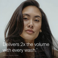 Woman with long voluminous dark hair showing Living Proof Full Conditioner delivering 2x the volume with every wash