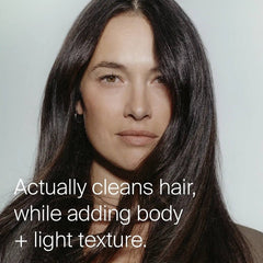 Woman with long glossy dark hair showing Living Proof dry shampoo cleaning while adding body and light texture