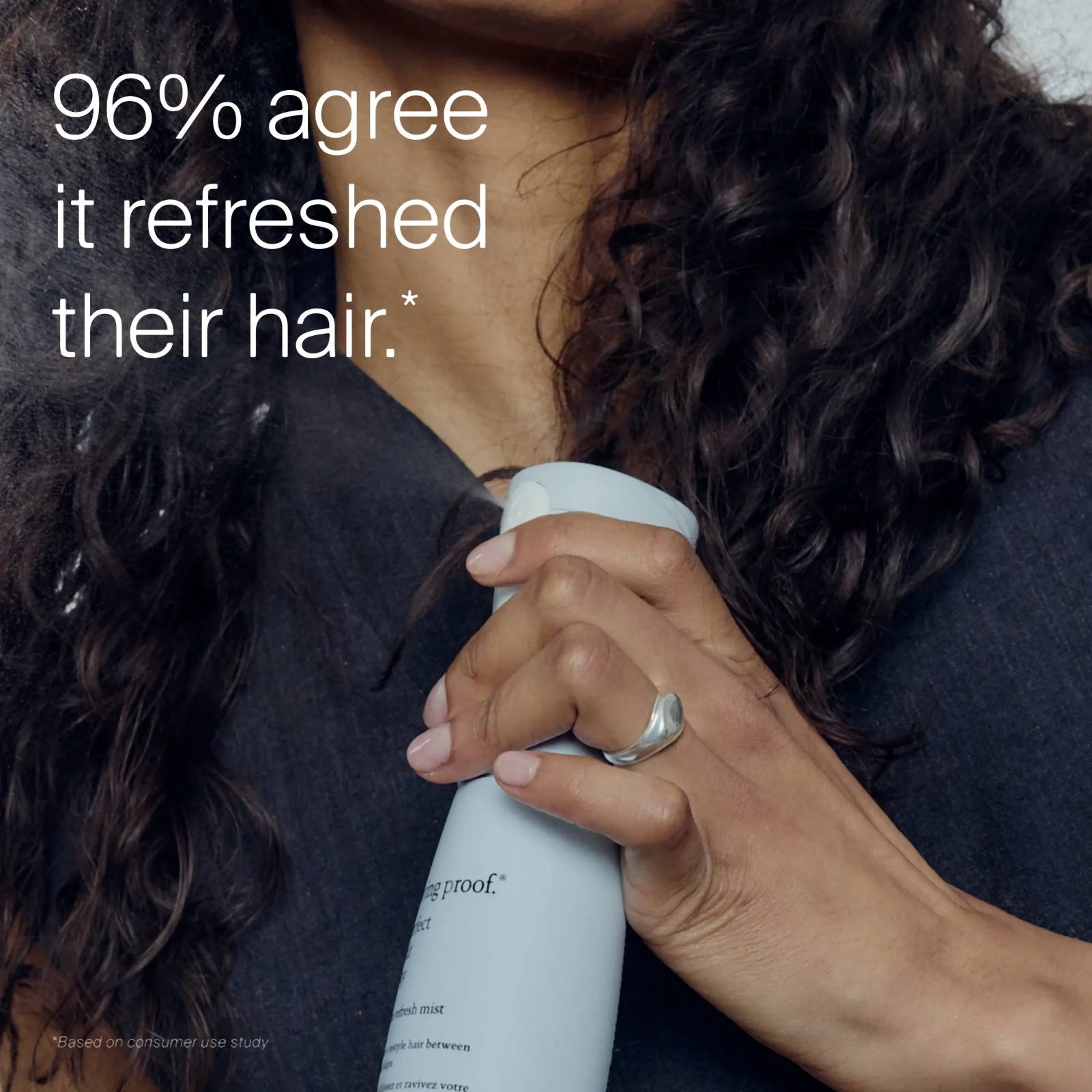 Hand spraying Style Refresh Mist on dark curly hair with 96% agreeing it refreshed their hair